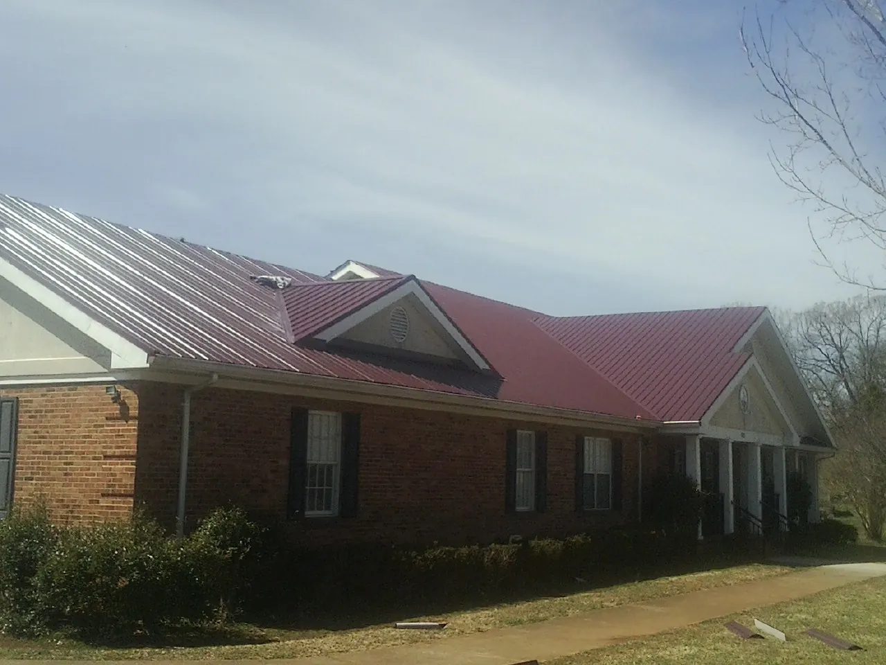 Red metal roof with gabled entries on a long brick building in Oswego