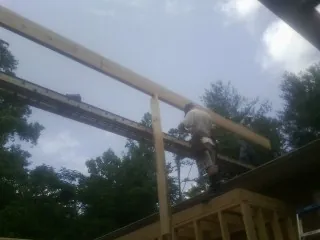 Carpenter setting a ridge beam over a new addition frame — Ice Dam Removal by Roofing Brothers in Oswego
