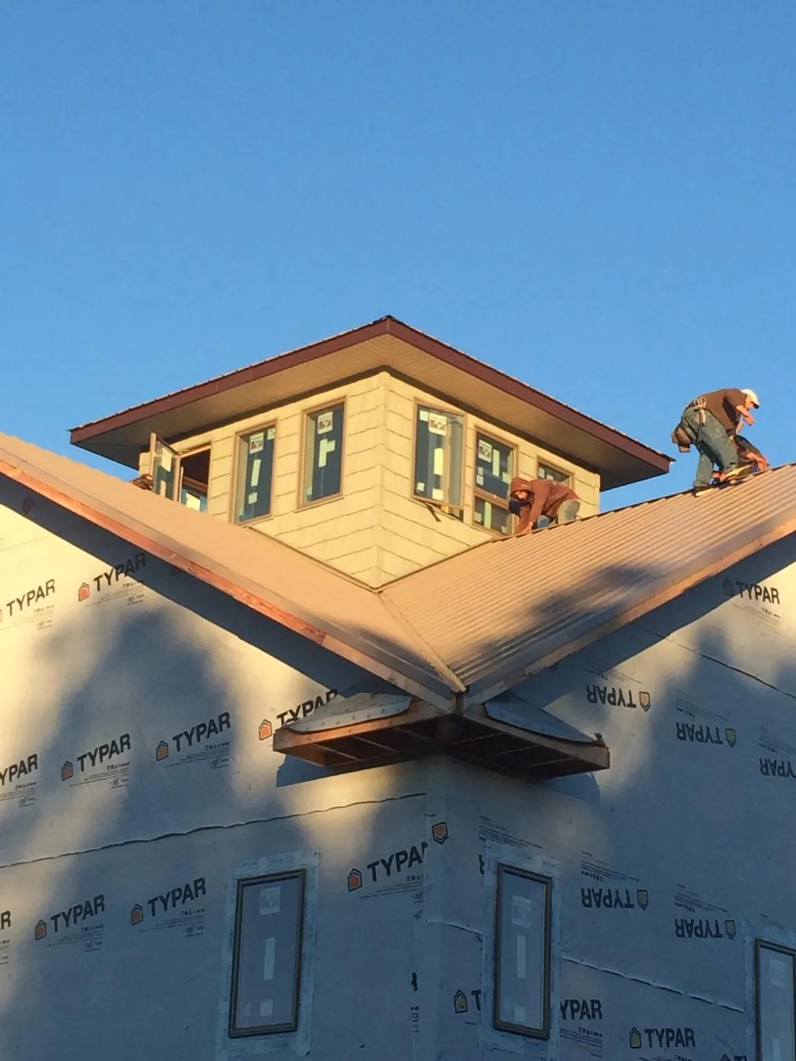 Roofers working around a rooftop cupola on a new metal roof at sunset — Roof Waterproofing in Oswego by Roofing Brothers